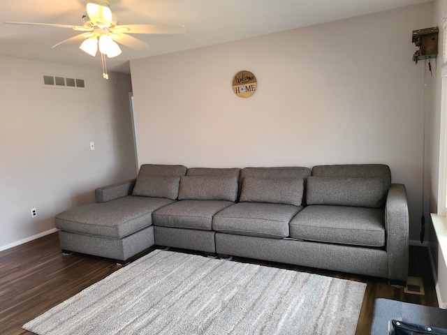 living room featuring visible vents, baseboards, wood finished floors, and a ceiling fan