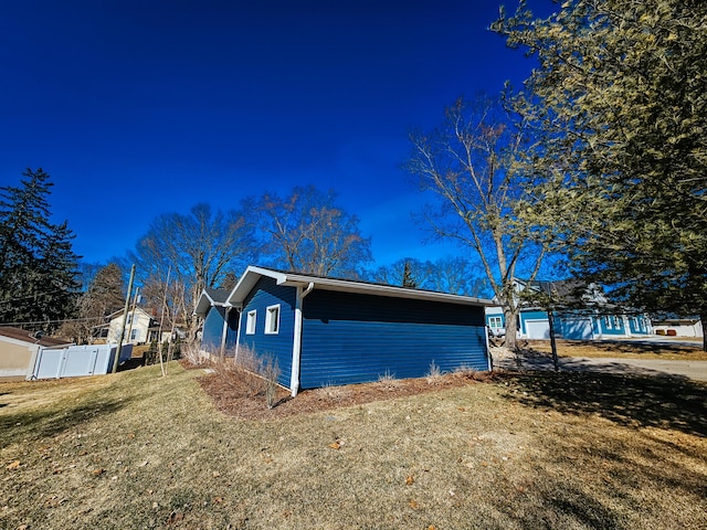 view of property exterior featuring a lawn and fence