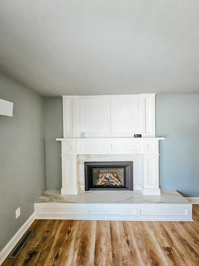 room details featuring visible vents, a fireplace, baseboards, and wood finished floors