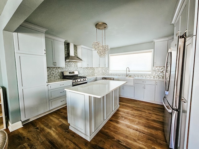 kitchen featuring dark wood-type flooring, a notable chandelier, stainless steel appliances, wall chimney exhaust hood, and light countertops