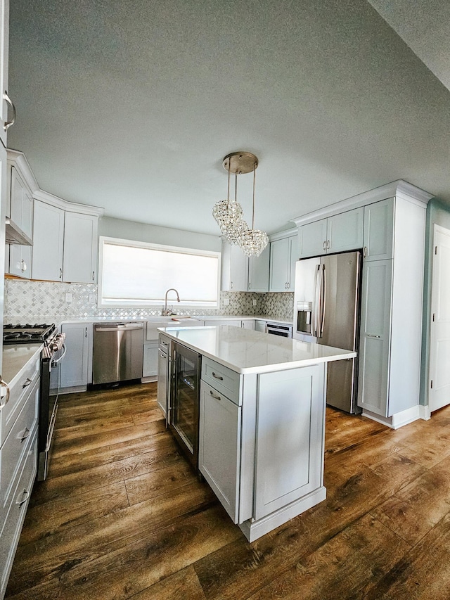 kitchen featuring a center island, dark wood-type flooring, beverage cooler, stainless steel appliances, and a sink