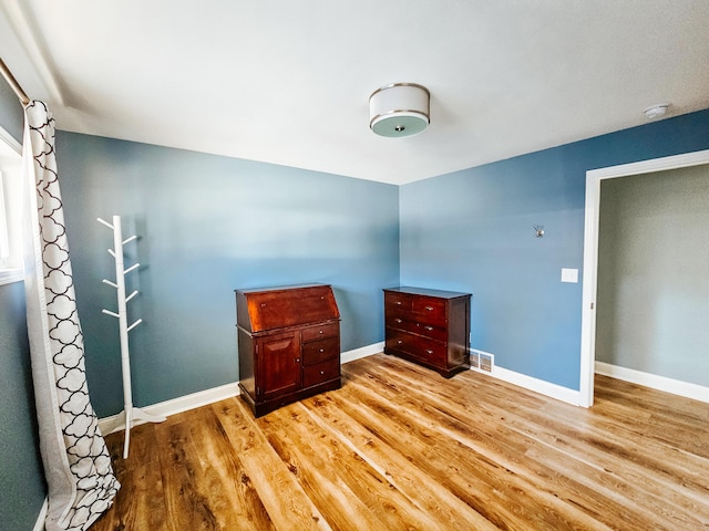 bedroom featuring visible vents, baseboards, and wood finished floors