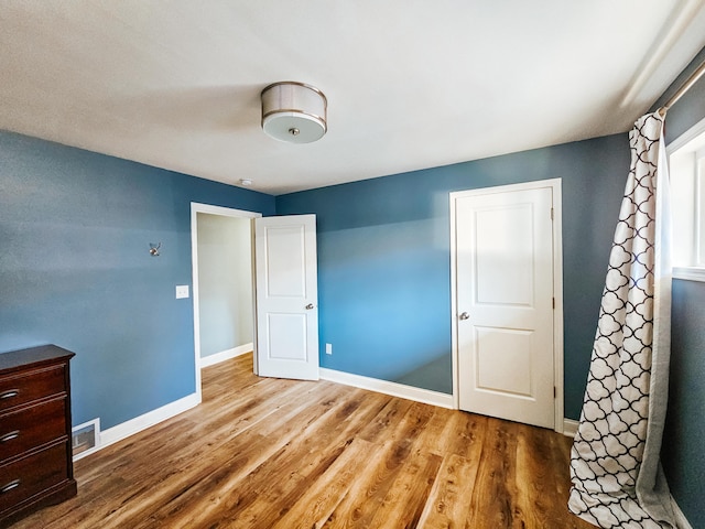 unfurnished bedroom featuring visible vents, baseboards, and wood finished floors