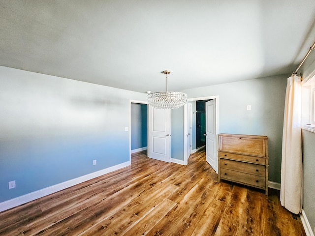 bedroom featuring baseboards, a notable chandelier, and wood finished floors