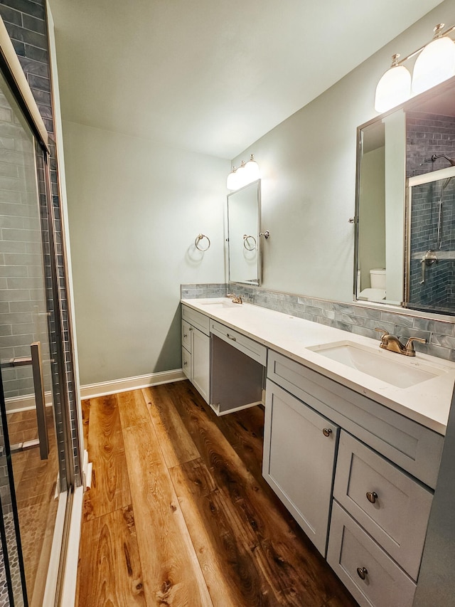 bathroom with double vanity, toilet, wood finished floors, and a sink