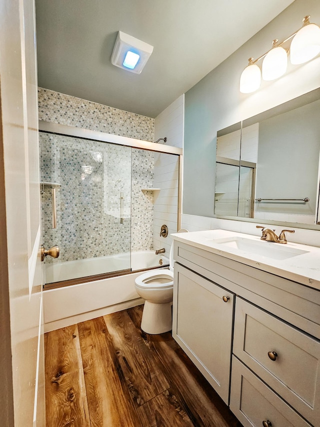 bathroom featuring shower / bath combination with glass door, toilet, vanity, and wood finished floors