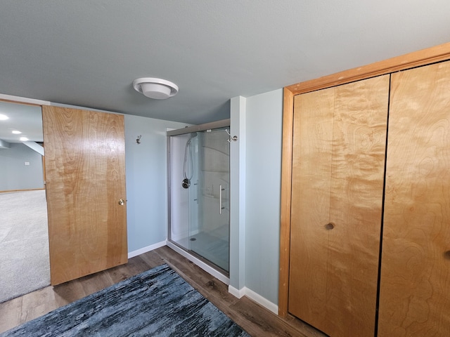 bathroom with wood finished floors, a stall shower, and baseboards