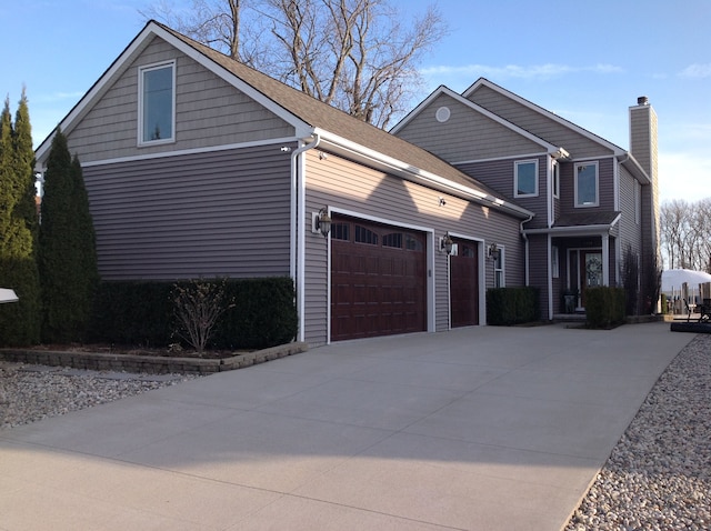 view of front facade featuring a garage, concrete driveway, and a chimney