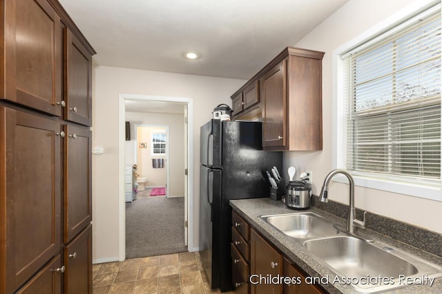 kitchen featuring dark countertops, plenty of natural light, baseboards, and a sink