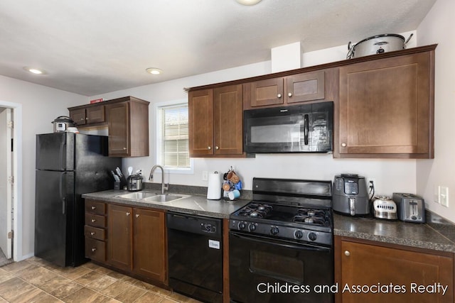 kitchen featuring dark countertops, recessed lighting, black appliances, and a sink