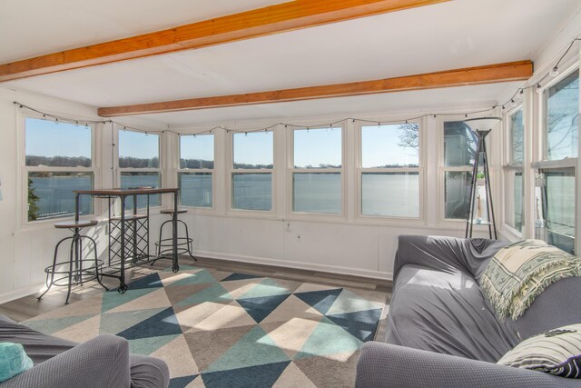 sunroom / solarium featuring beam ceiling and a healthy amount of sunlight