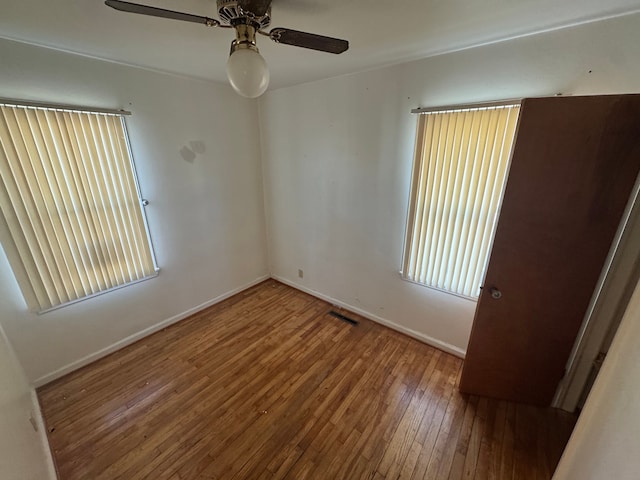 unfurnished room with visible vents, baseboards, ceiling fan, and hardwood / wood-style floors