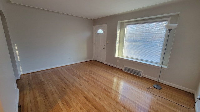 foyer with light wood-style flooring, baseboards, and visible vents