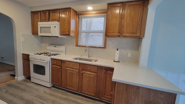 kitchen with white appliances, light countertops, light wood-style floors, and a sink