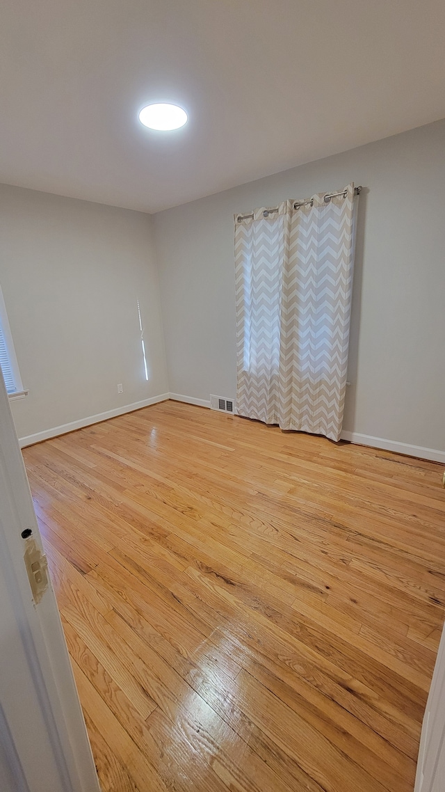 spare room featuring visible vents, baseboards, and light wood-style flooring