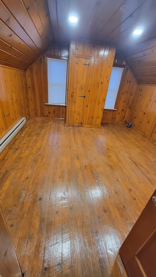 additional living space featuring vaulted ceiling, wood walls, wood ceiling, and hardwood / wood-style floors