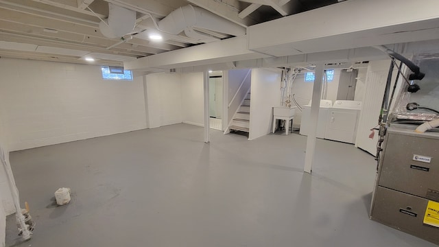 basement with stairs, separate washer and dryer, heating unit, concrete block wall, and a sink