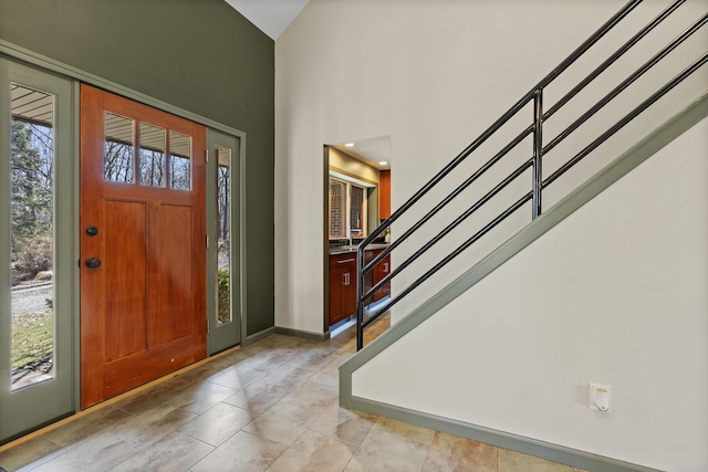 entrance foyer with stairway, baseboards, a high ceiling, and a healthy amount of sunlight