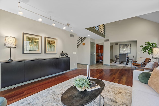 living room with track lighting, wood finished floors, visible vents, and baseboards