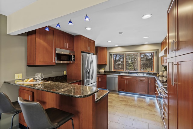 kitchen with a peninsula, dark stone countertops, recessed lighting, and stainless steel appliances