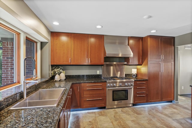 kitchen featuring a sink, dark stone countertops, recessed lighting, wall chimney exhaust hood, and high end range