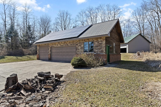 view of side of home featuring concrete driveway, roof mounted solar panels, a garage, a yard, and stone siding