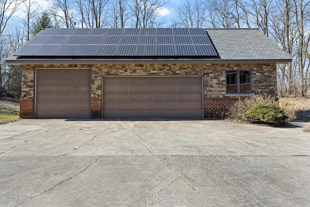 garage with solar panels and concrete driveway