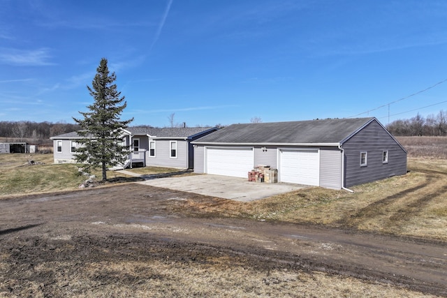 view of front of house with concrete driveway, a garage, and a shingled roof