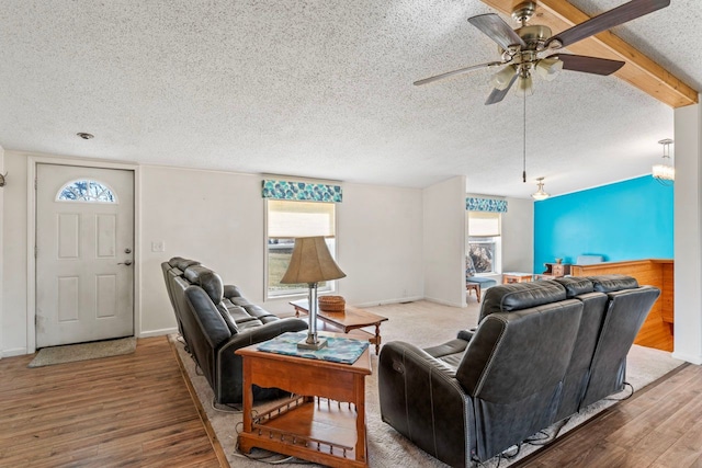 living room with baseboards, a textured ceiling, wood finished floors, and a ceiling fan