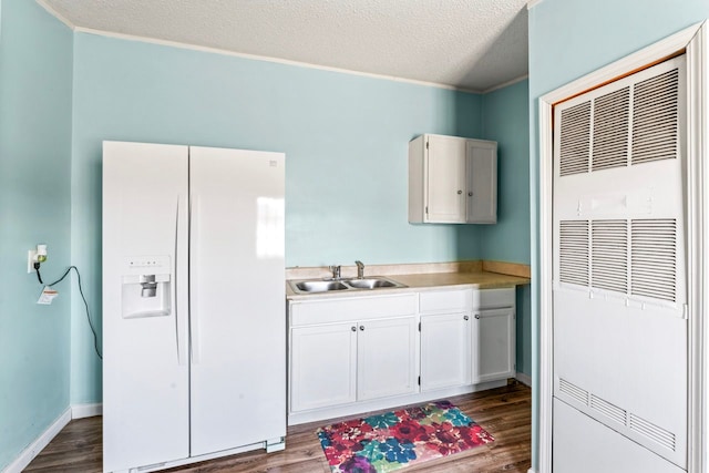 kitchen featuring a sink, dark wood finished floors, white fridge with ice dispenser, light countertops, and a heating unit