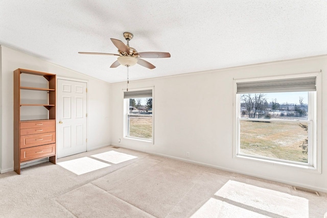 unfurnished bedroom featuring visible vents, lofted ceiling, carpet, and a textured ceiling