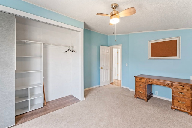 unfurnished office with carpet, a ceiling fan, baseboards, ornamental molding, and a textured ceiling