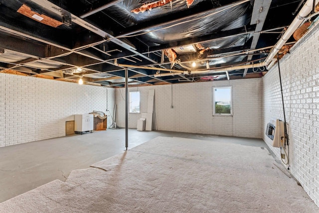 basement featuring heating unit and brick wall