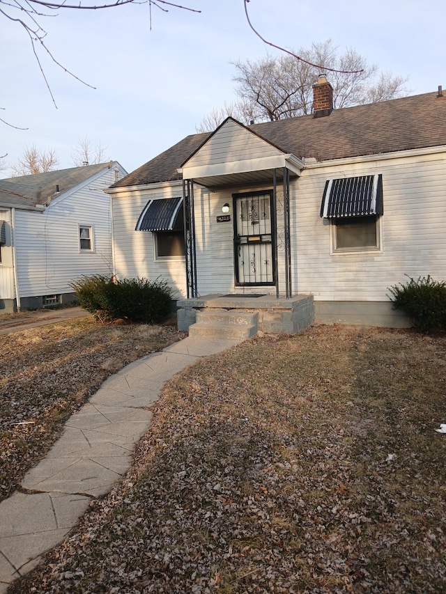 view of front of home featuring a chimney and a shingled roof