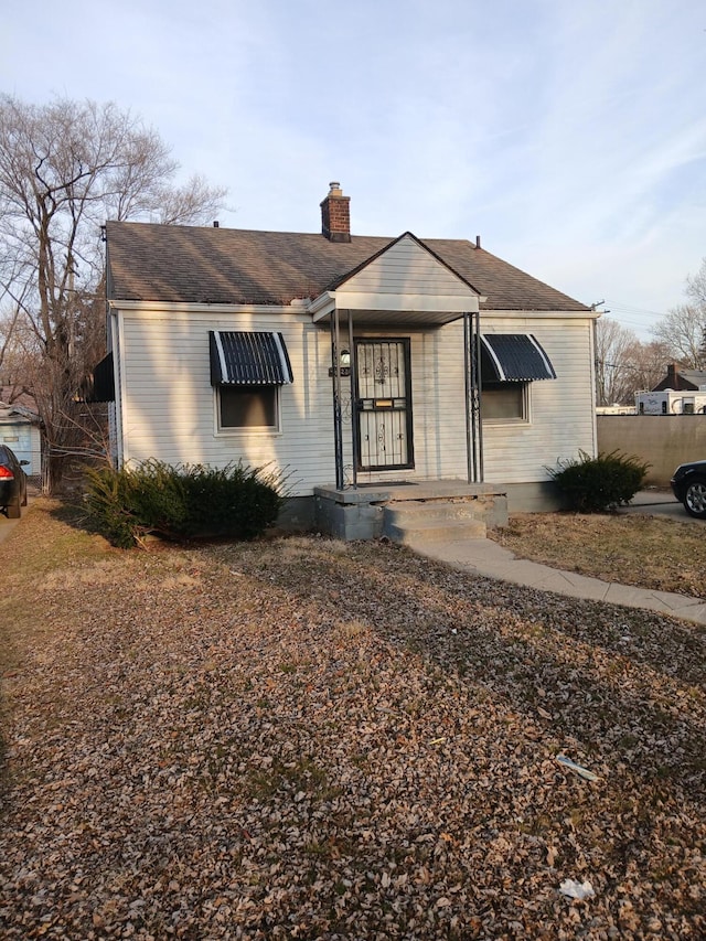 view of front of home with a chimney and a shingled roof