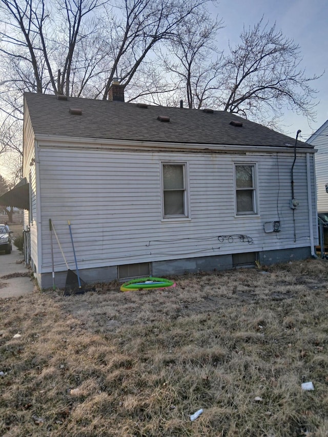 view of side of home with a chimney and a shingled roof