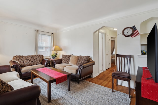 living room with baseboards, arched walkways, and wood finished floors