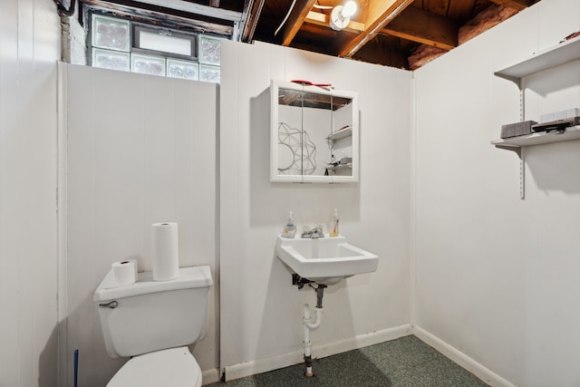 bathroom featuring toilet, baseboards, and a sink