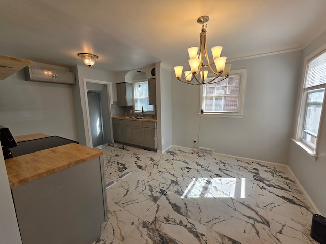 unfurnished dining area with visible vents, baseboards, an inviting chandelier, marble finish floor, and a sink