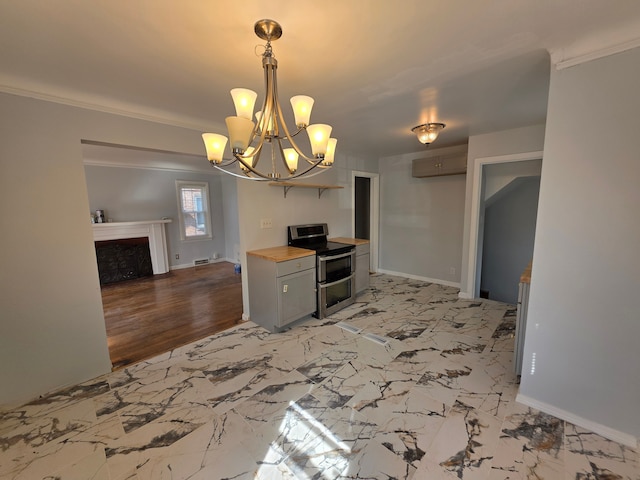 kitchen with an inviting chandelier, double oven range, marble finish floor, and baseboards