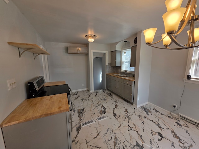 kitchen featuring visible vents, a chandelier, butcher block counters, marble finish floor, and a sink