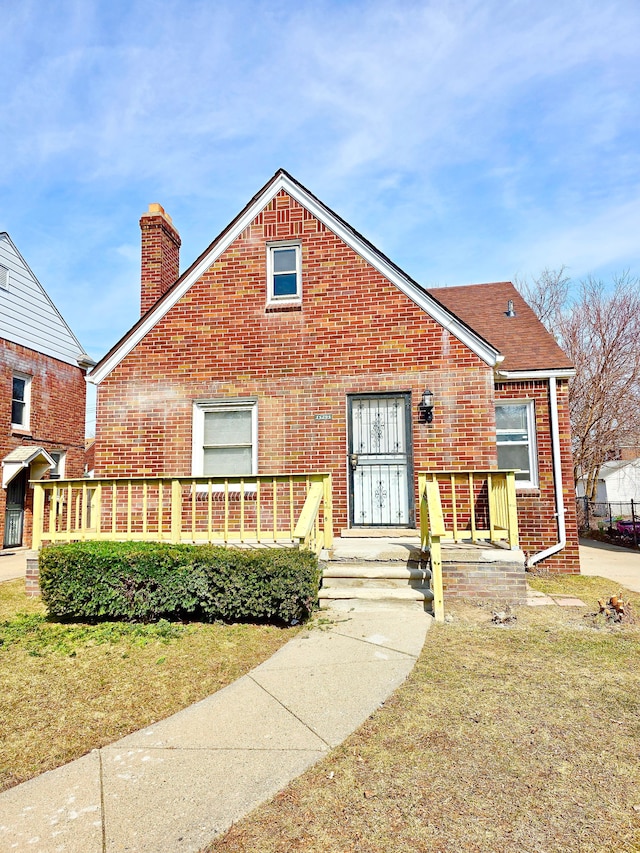 view of front of property with a front yard, brick siding, and a chimney