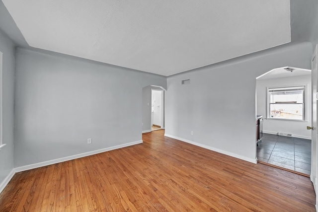 spare room featuring visible vents, wood finished floors, and arched walkways