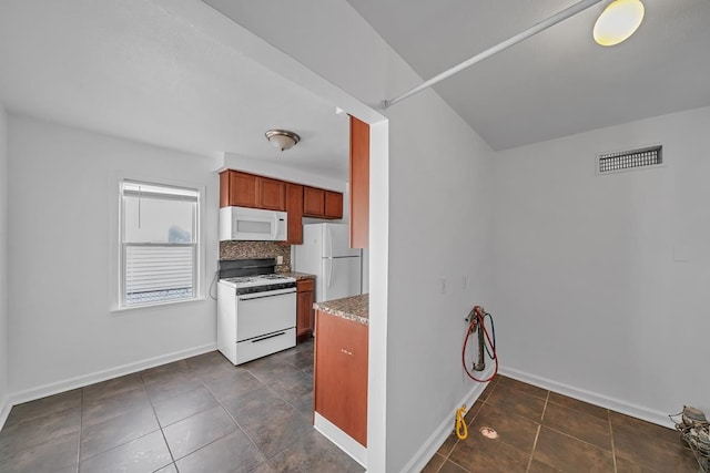 kitchen with white appliances, baseboards, visible vents, decorative backsplash, and dark tile patterned floors