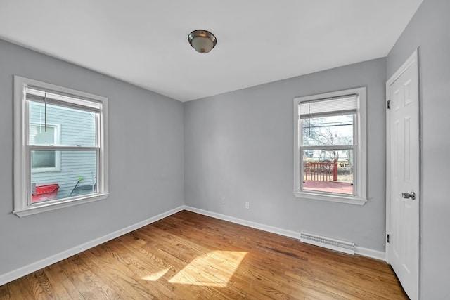 empty room with visible vents, light wood-type flooring, and baseboards