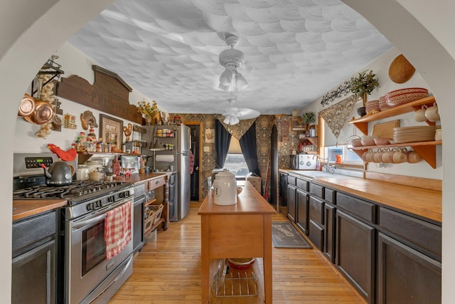 kitchen with open shelves, stainless steel appliances, wooden counters, and light wood-style floors