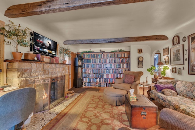 living room featuring a stone fireplace, beam ceiling, and arched walkways