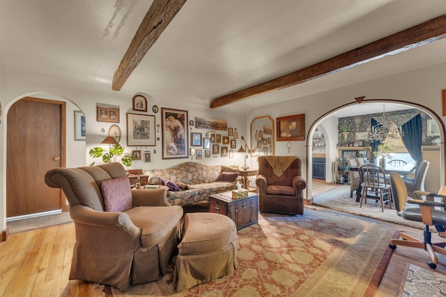 living area featuring arched walkways, beam ceiling, and hardwood / wood-style flooring