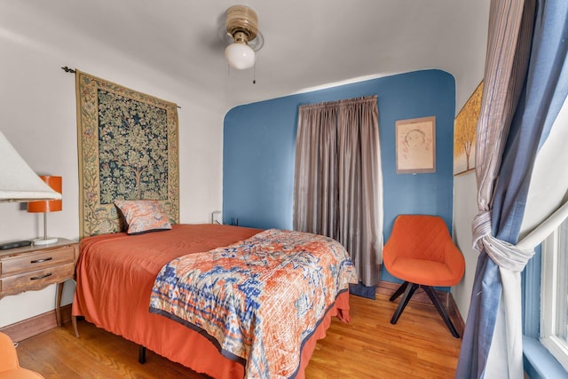 bedroom featuring ceiling fan, baseboards, and wood finished floors