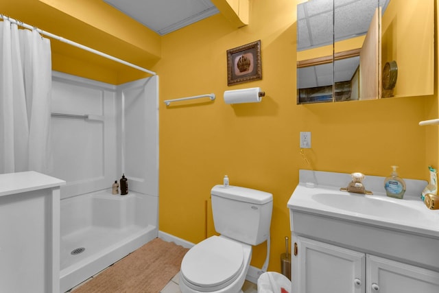 bathroom featuring toilet, a stall shower, vanity, and baseboards